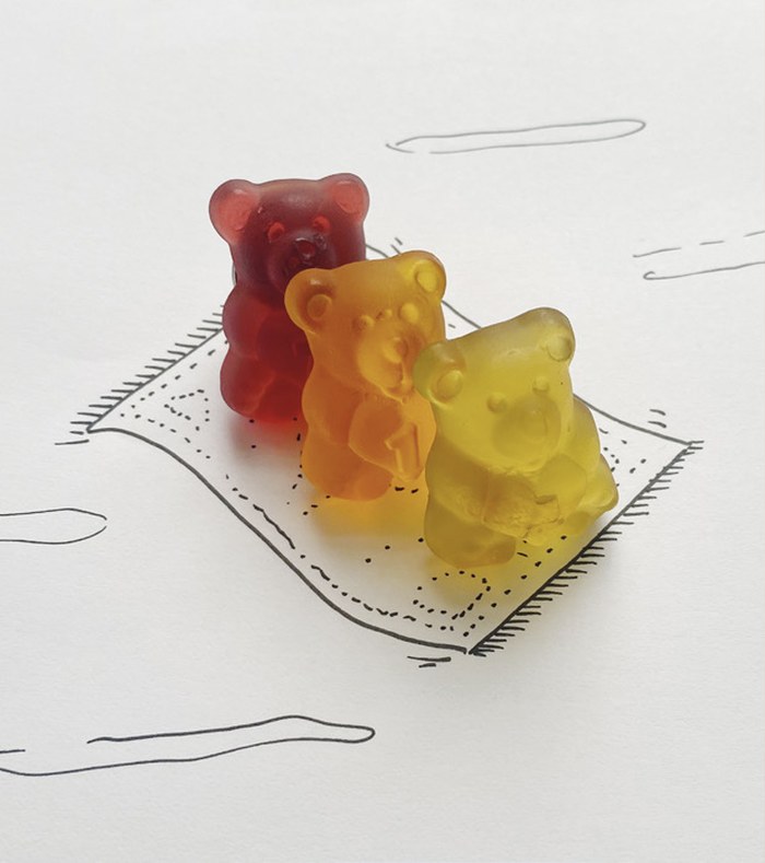 Drei Fruchtsaftbären in Rot, Orange und Gelb sitzen auf einer gezeichneten Picknickdecke