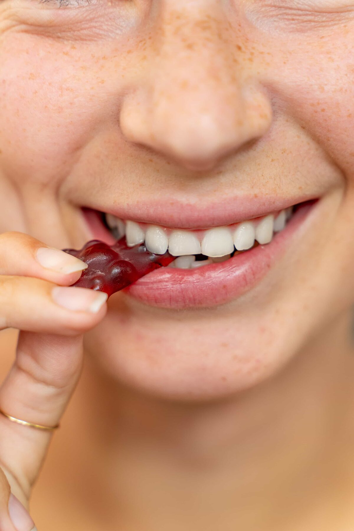 Frau beißt lächelnd in einen NATURFEH Fruchtsaftbären